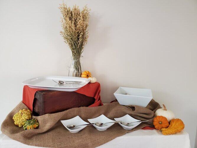 Decorative display with dishes, pumpkins, and decorative dried plants for seasonal home decor and buffet-style table setting, styled in a cozy, rustic arrangement.